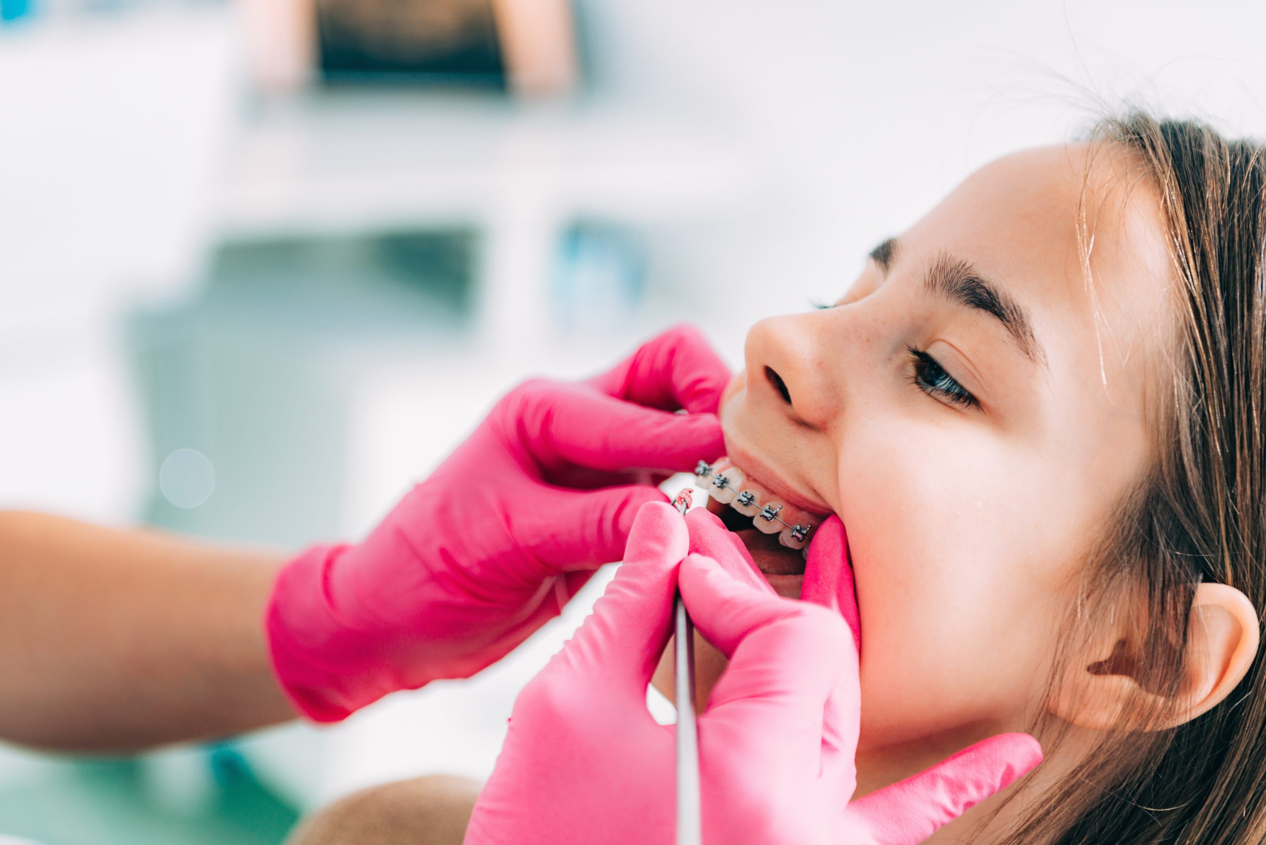 Orthodontist checking girl’s dental braces